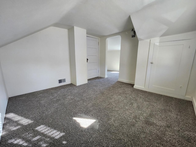 additional living space featuring lofted ceiling, carpet, visible vents, and arched walkways