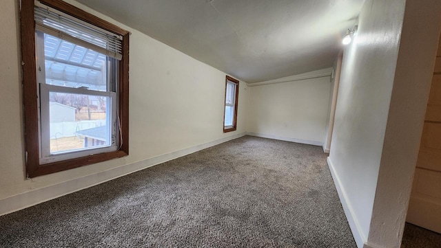 unfurnished room with baseboards, carpet, a healthy amount of sunlight, and vaulted ceiling