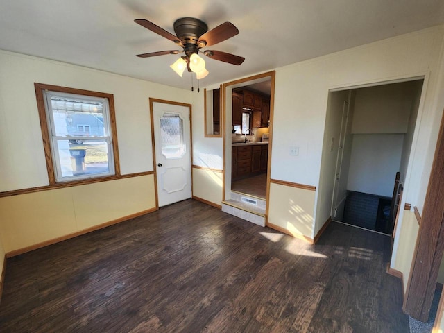 unfurnished bedroom featuring a sink, baseboards, a ceiling fan, and dark wood-style flooring