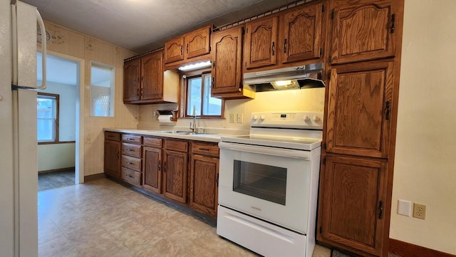 kitchen featuring baseboards, under cabinet range hood, light countertops, white range with electric stovetop, and a sink