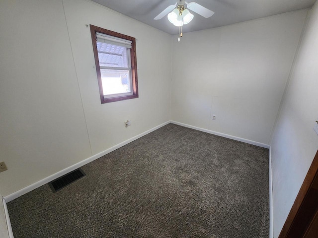 spare room featuring visible vents, dark carpet, a ceiling fan, and baseboards