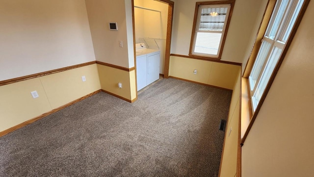 empty room with washer and clothes dryer, visible vents, light colored carpet, and baseboards