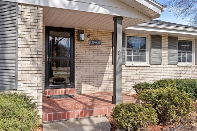 property entrance featuring brick siding and covered porch