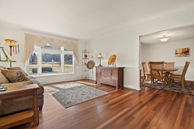 living area featuring wood finished floors, baseboards, and ornamental molding