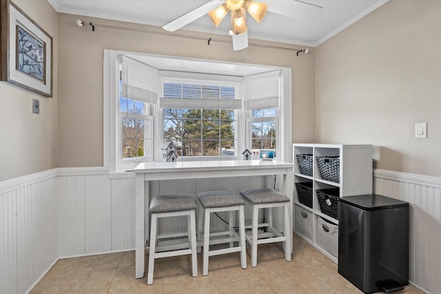 tiled office featuring wainscoting and a ceiling fan