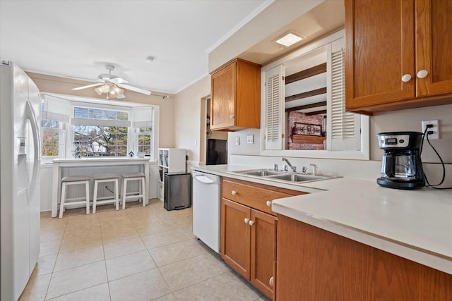 kitchen featuring white appliances, brown cabinetry, and a sink