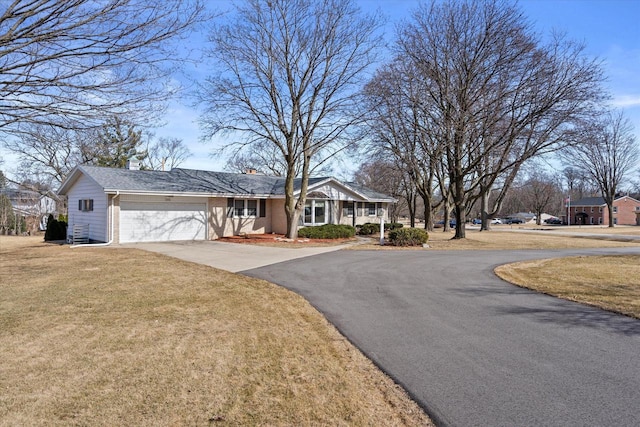 view of front of house featuring brick siding, a front yard, a chimney, a garage, and driveway