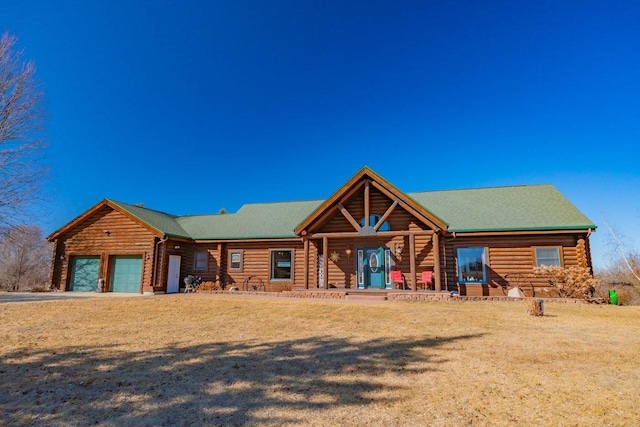 cabin with covered porch, log exterior, a front lawn, and an attached garage