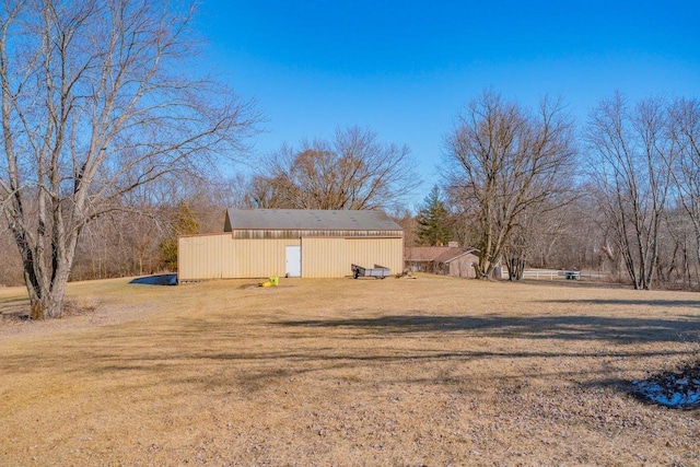 view of side of property featuring a pole building, a yard, and an outdoor structure