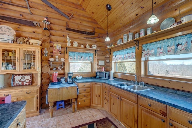 kitchen with dark countertops, vaulted ceiling, a sink, and hanging light fixtures