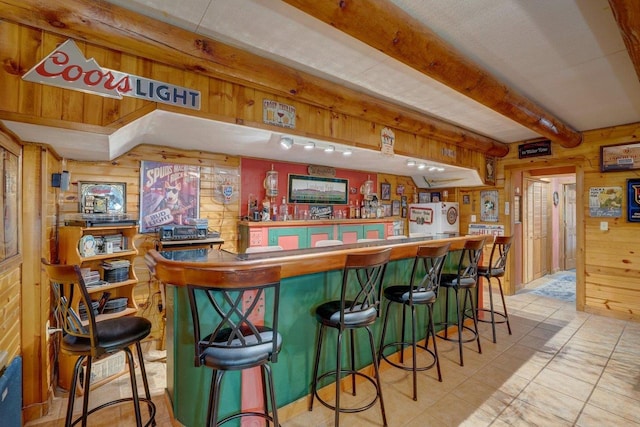 bar with beam ceiling, wood walls, and a dry bar