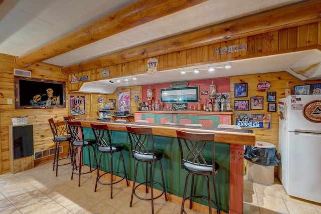 bar with wooden walls, visible vents, beamed ceiling, and freestanding refrigerator