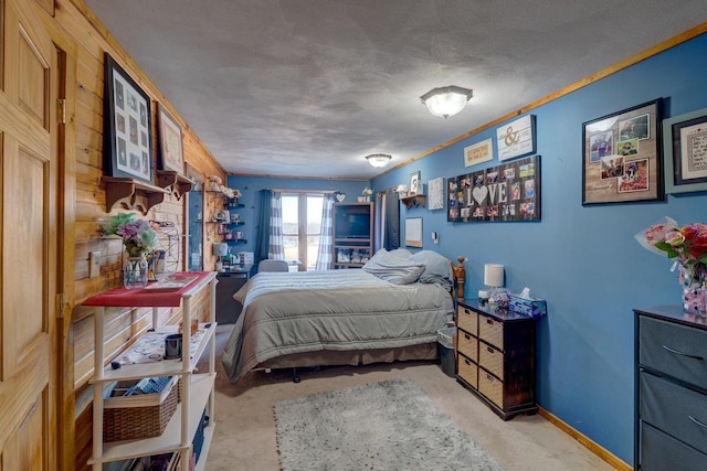 bedroom with baseboards, a textured ceiling, and light colored carpet