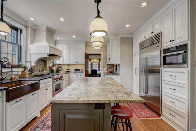 kitchen featuring a sink, a kitchen island, white cabinets, and premium appliances