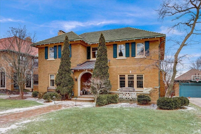 view of front of home featuring an outbuilding, brick siding, a chimney, and a front yard