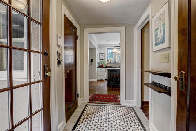 doorway featuring light tile patterned flooring and baseboards