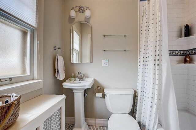 bathroom with baseboards, shower / tub combo with curtain, a sink, and toilet