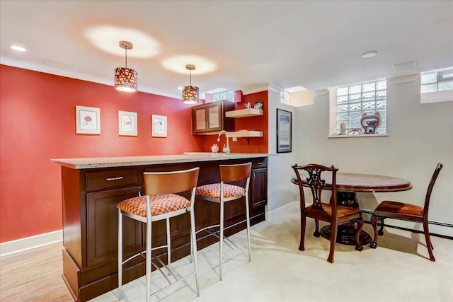 interior space with a baseboard heating unit, bar area, baseboards, decorative light fixtures, and crown molding