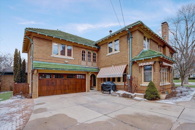 view of front of property with driveway, an attached garage, a chimney, and brick siding