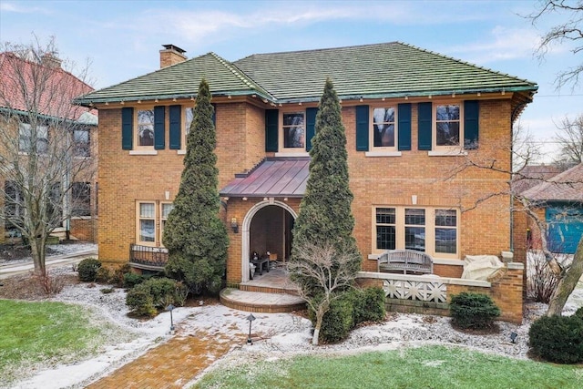 view of front of property with a chimney and brick siding