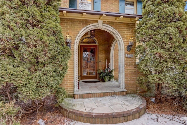 doorway to property with brick siding and a porch