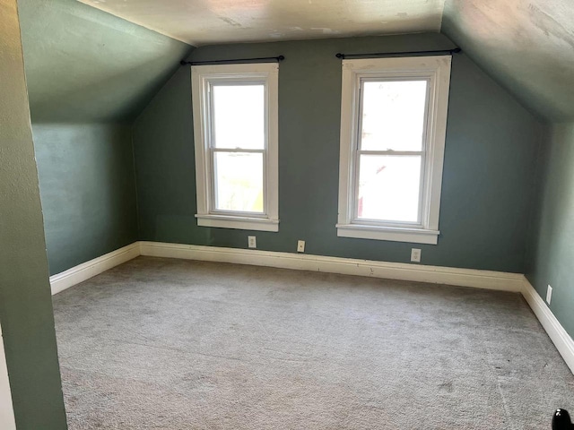 additional living space featuring baseboards, lofted ceiling, and carpet