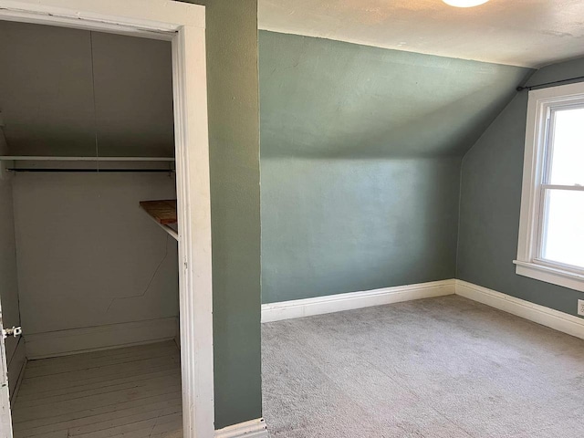 additional living space with baseboards, lofted ceiling, and carpet flooring