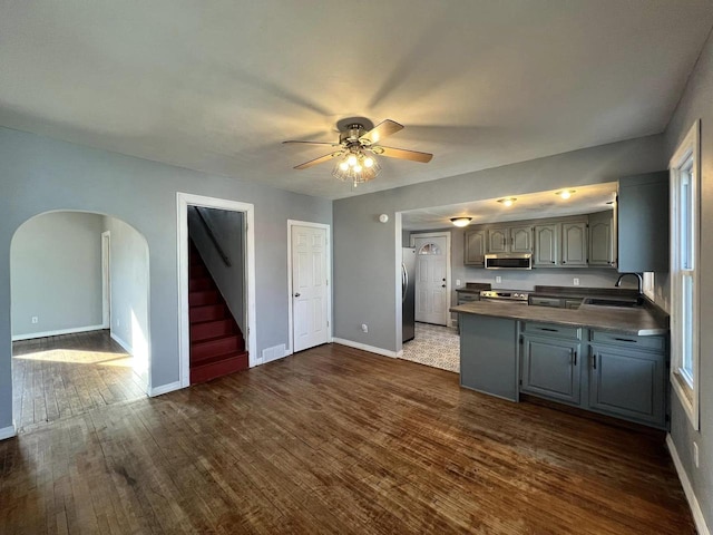 kitchen featuring dark countertops, dark wood-type flooring, gray cabinets, appliances with stainless steel finishes, and a sink