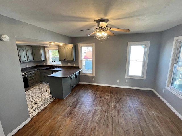 kitchen featuring dark countertops, baseboards, dark wood-style flooring, plenty of natural light, and a sink