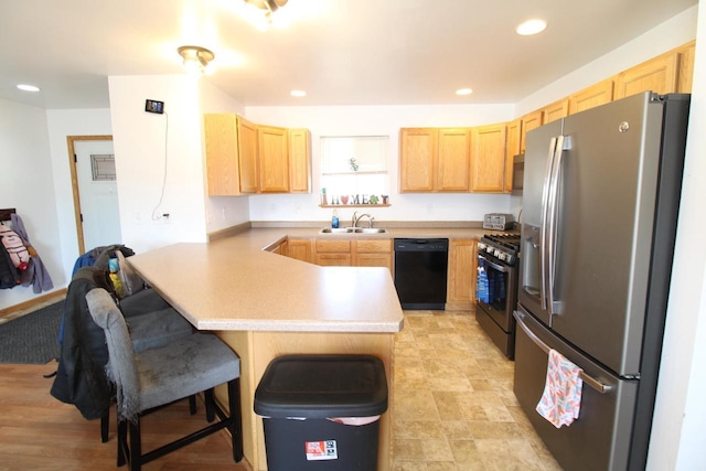 kitchen featuring recessed lighting, a peninsula, a breakfast bar, appliances with stainless steel finishes, and light brown cabinetry