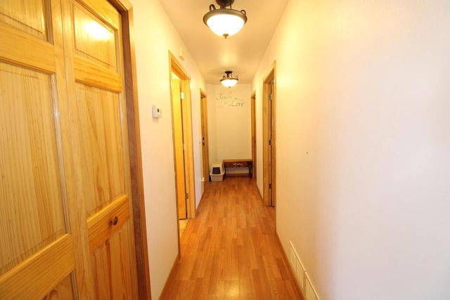 hallway featuring light wood finished floors and baseboards