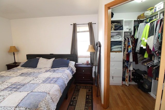 bedroom featuring a spacious closet, a closet, and wood finished floors