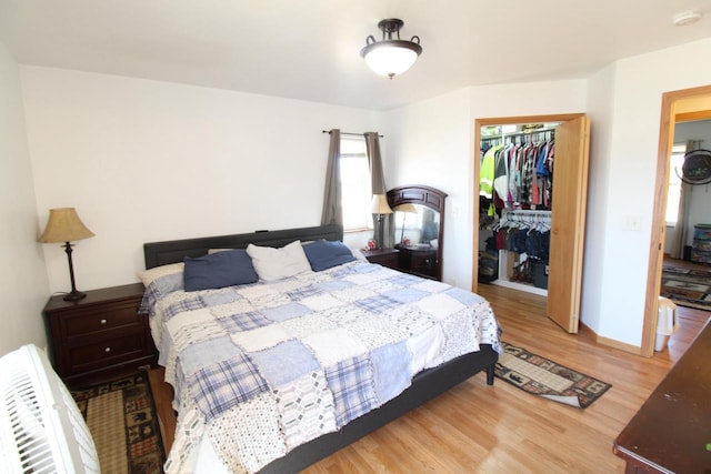 bedroom featuring a closet, a walk in closet, light wood-style flooring, and baseboards