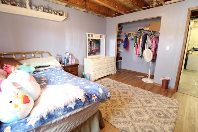 bedroom with washer / clothes dryer, a closet, and wood finished floors