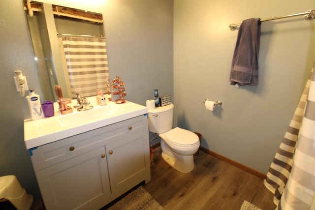 bathroom with a shower with shower curtain, toilet, vanity, wood finished floors, and baseboards