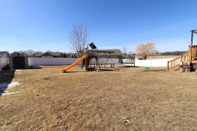 view of play area featuring an outbuilding, a yard, a shed, and a fenced backyard