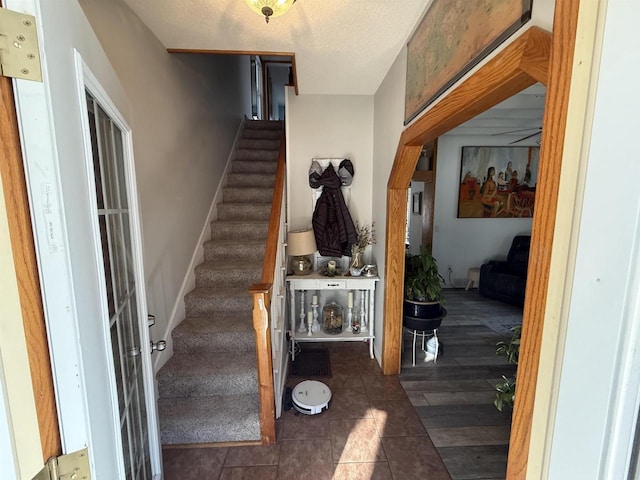 stairs featuring a textured ceiling and wood finished floors