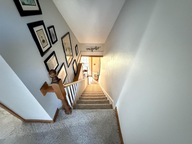 stairway with baseboards and carpet flooring