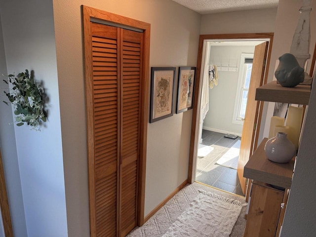 hallway featuring a textured ceiling and baseboards