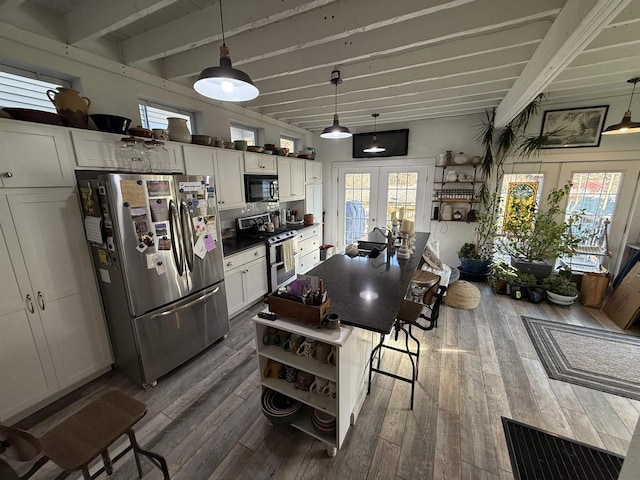 kitchen with appliances with stainless steel finishes, white cabinets, beamed ceiling, and french doors