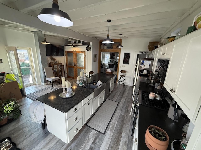 kitchen featuring hanging light fixtures, dark wood-type flooring, white cabinetry, a sink, and beamed ceiling