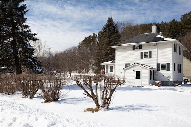 snow covered back of property with a chimney