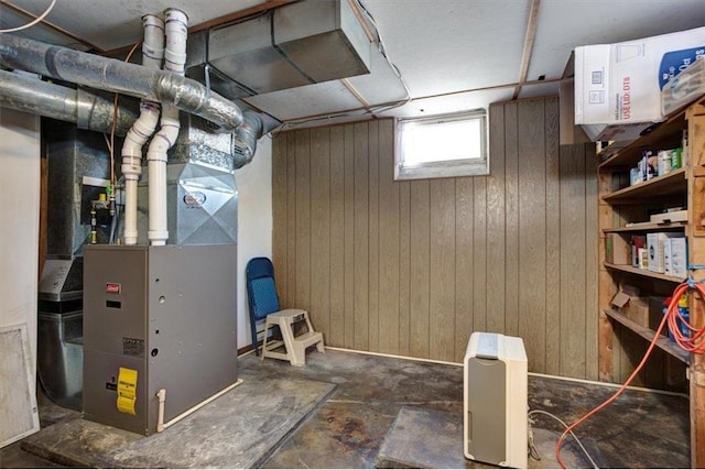 basement featuring wooden walls and heating unit