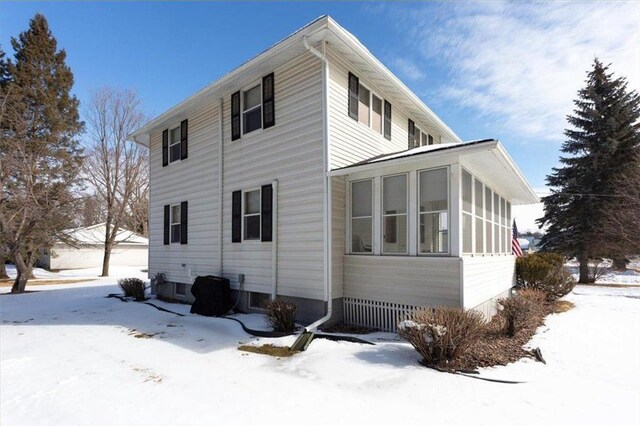 view of snow covered exterior with a sunroom