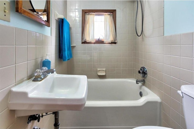 full bath with a sink, toilet, tile walls, and shower / bathtub combination