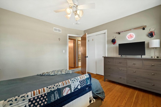 bedroom with wood finished floors, visible vents, a closet, and ceiling fan