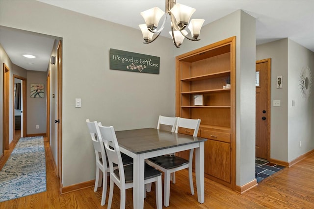 dining room with an inviting chandelier, baseboards, and light wood-type flooring