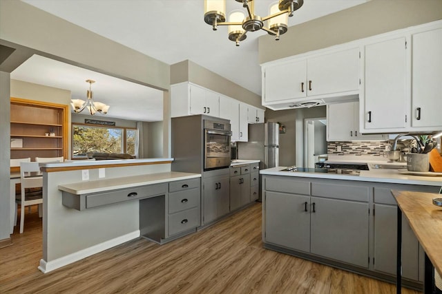 kitchen with stainless steel appliances, a notable chandelier, a peninsula, and gray cabinets