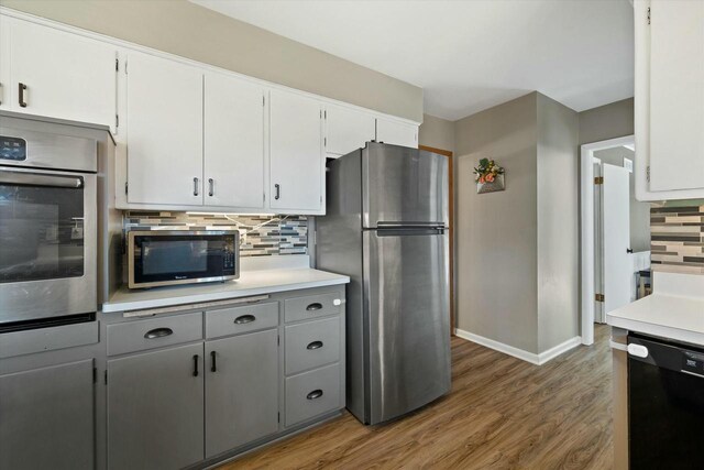 kitchen with decorative backsplash, stainless steel appliances, light countertops, and wood finished floors