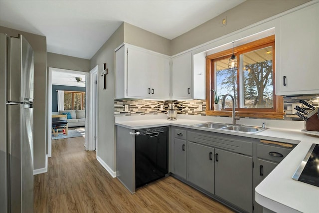 kitchen with dishwasher, light countertops, freestanding refrigerator, and a sink